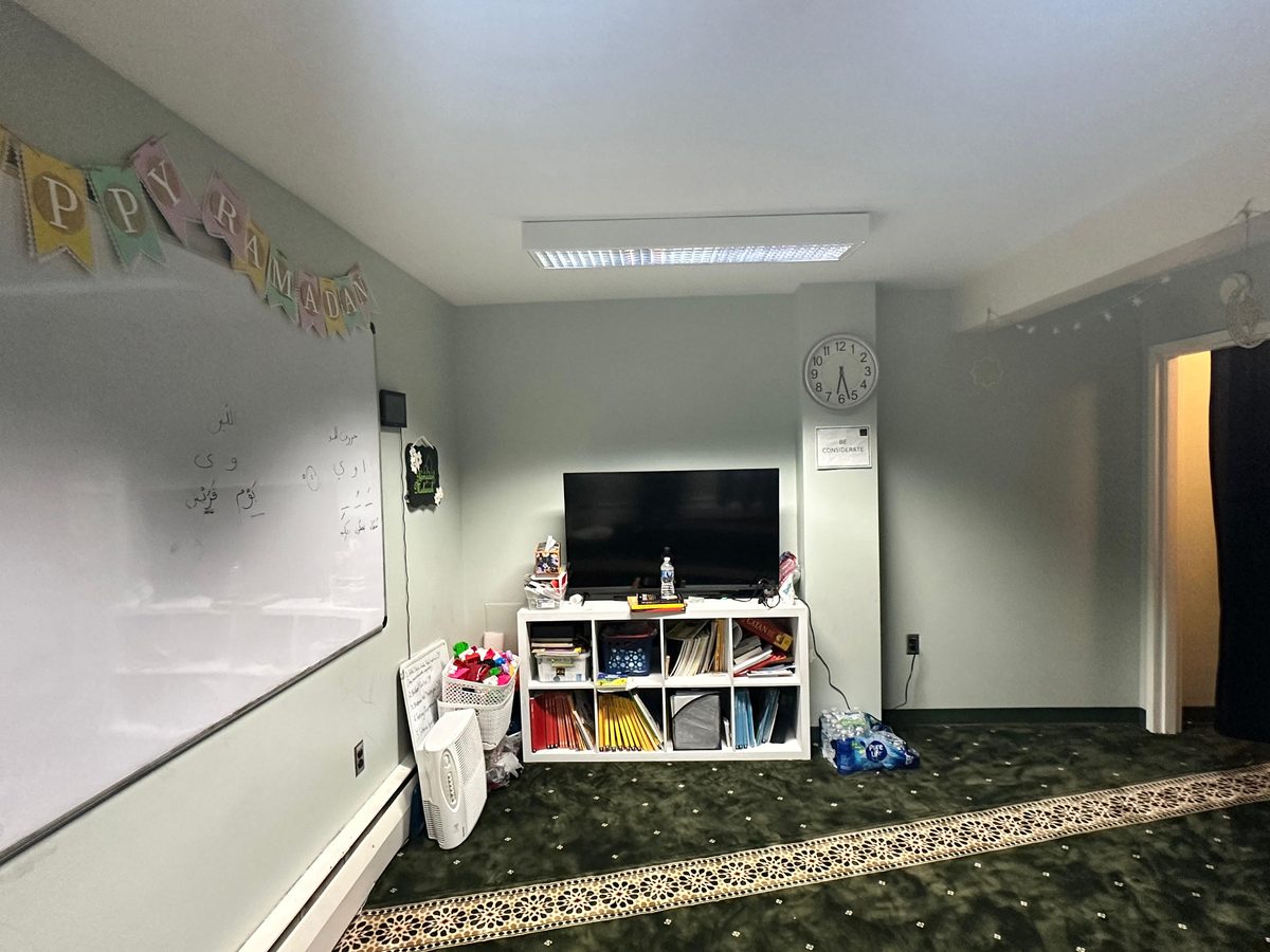 Another view of the renovated prayer room with new carpet, a TV and children's shelves