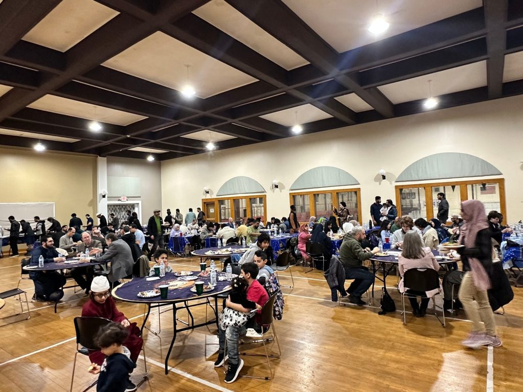 Children eat at a round table in the foreground as families and guests fill the tables across the ballroom.