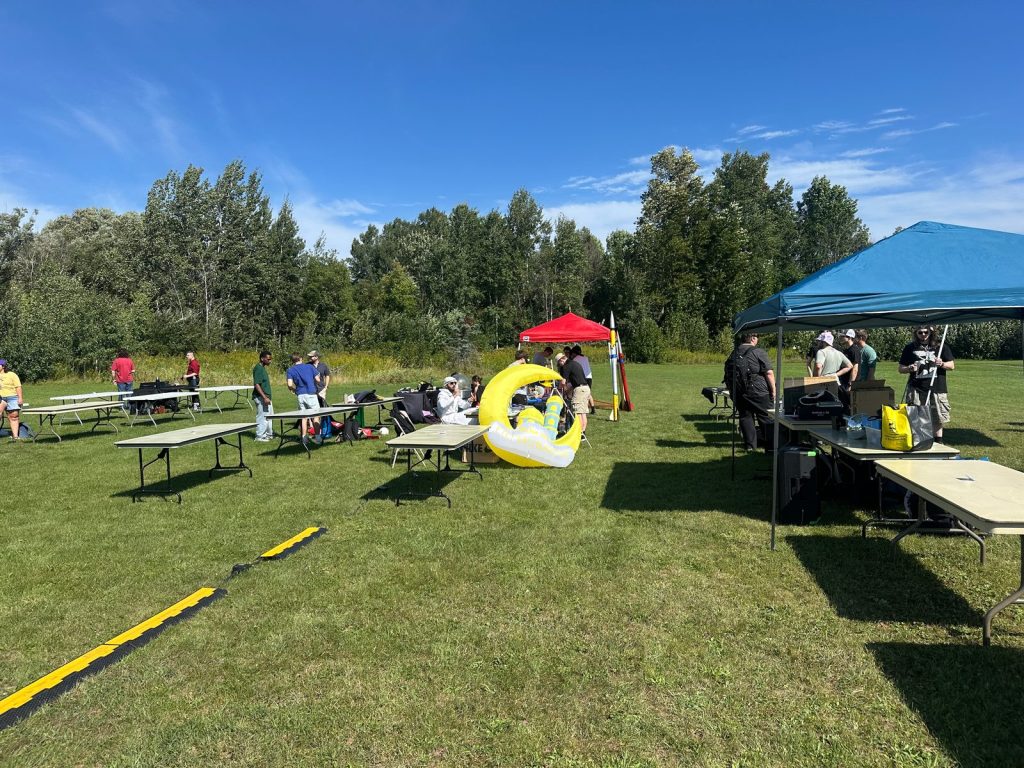 Student groups set up tables and tents on a sunny lawn, with MSA's yellow crescent inflatable in the middle.